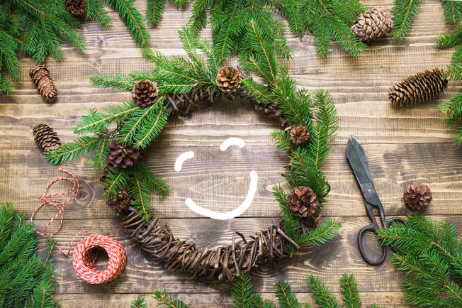 Christmas wreath with fir branches and pine cone on wooden tabletop. Flat lay.